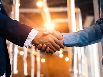 Two individuals shaking hands in suits