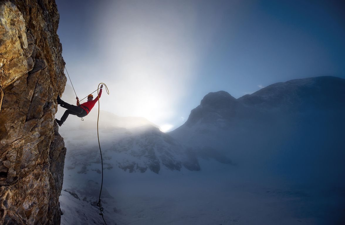 Climbing up a mountain against the backdrop of a blue sky and sunshine coming through