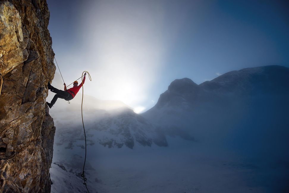 Climbing up a mountain against the backdrop of a blue sky and sunshine coming through