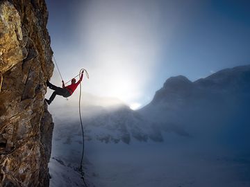 Climbing up a mountain against the backdrop of a blue sky and sunshine coming through