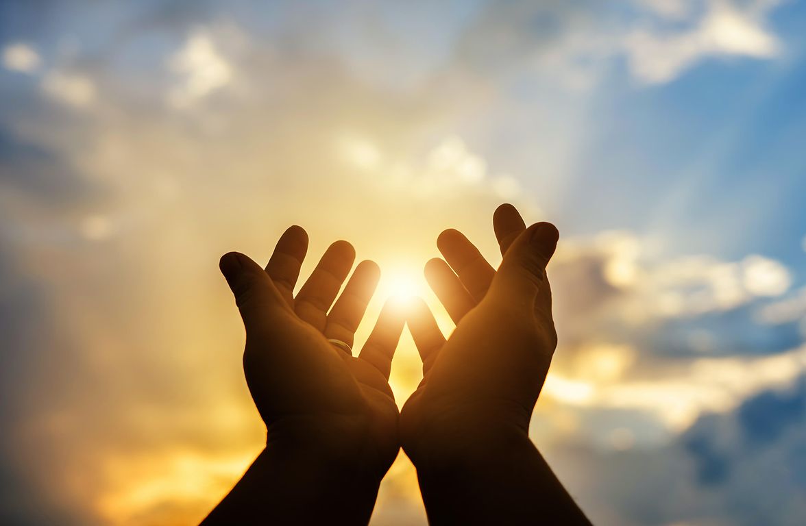 Hands clasped and held up to the sky representing faith.