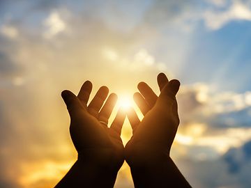 Hands clasped and held up to the sky representing faith.