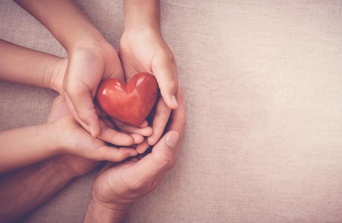 Several pairs of hands holding a heart.