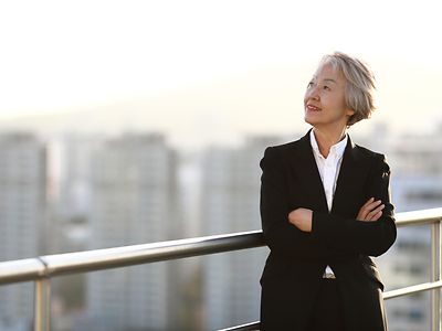 woman in suit looking out from balcony