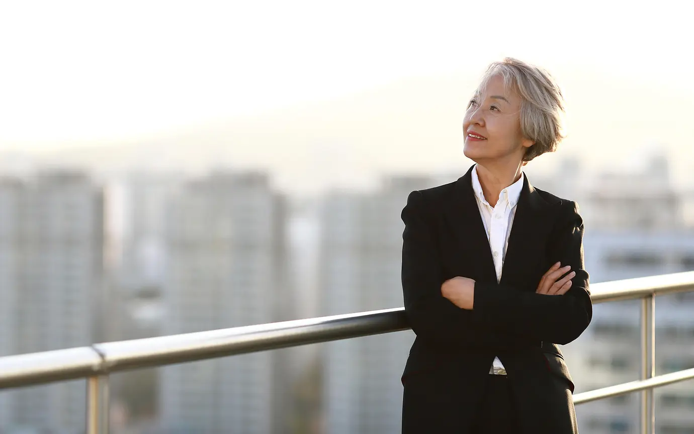 woman in suit looking out from balcony