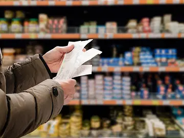 person standing in supermarket checking receipts
