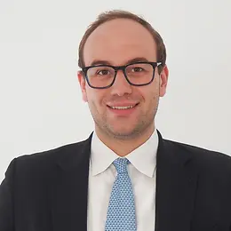 A man in a suit and tie smiles at the camera.