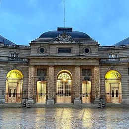 Through a stone archway, you look out onto a courtyard with a historic building at its head