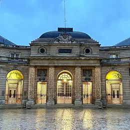 Through a stone archway, you look out onto a courtyard with a historic building at its head