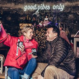 A woman and a man wearing down jackets are sitting in a restaurant in a kind of barn. They seem happy and familiar.