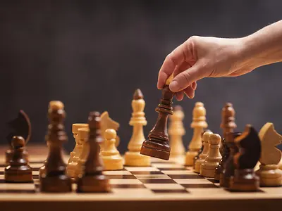 chess piece in a woman's hand on a chessboard in an office