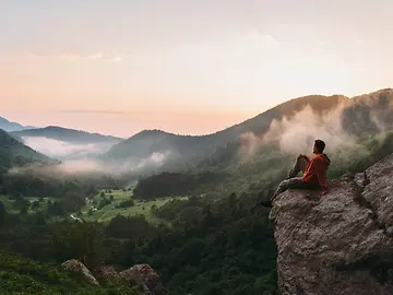 Young man sitting on rocky stone and enjoying view