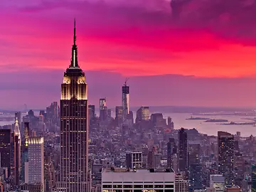 Empire State building in New York skyline with a red and purple night sky at sunset.