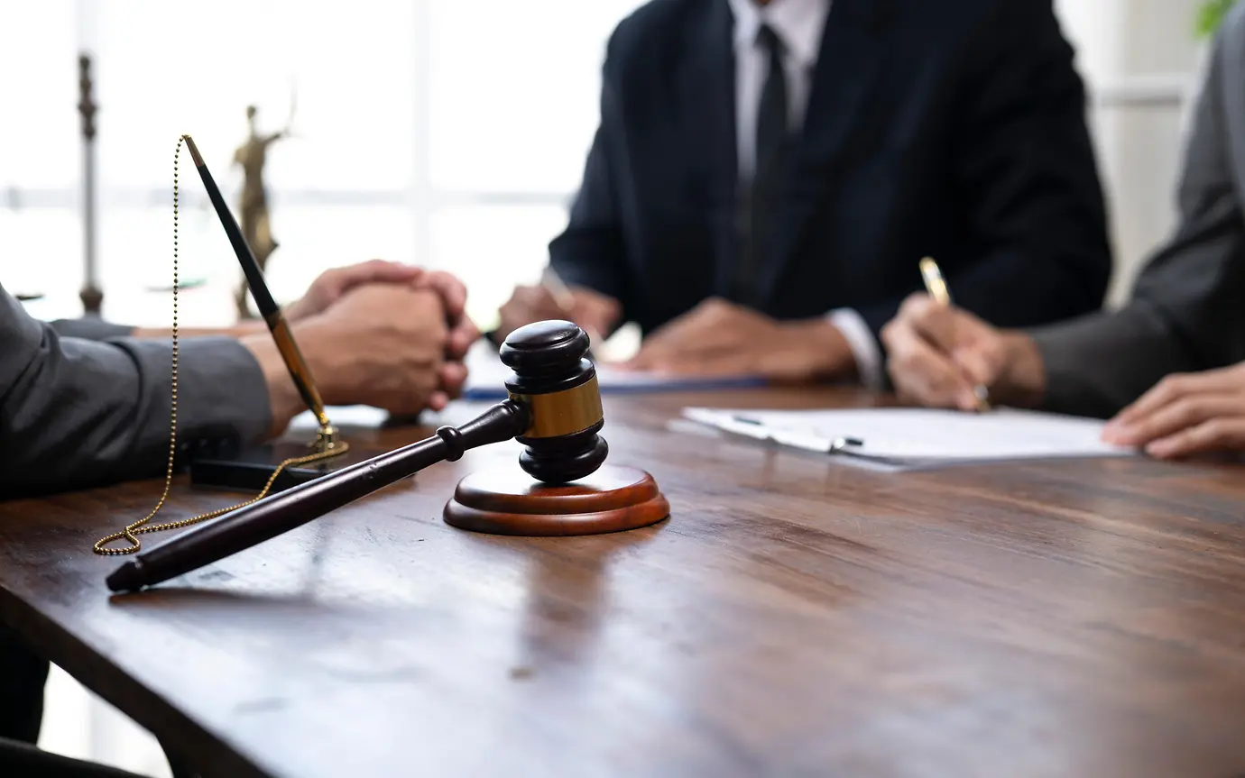 Lawyers are discussing a contract with a gavel on the table, emphasizing legal proceedings and agreements